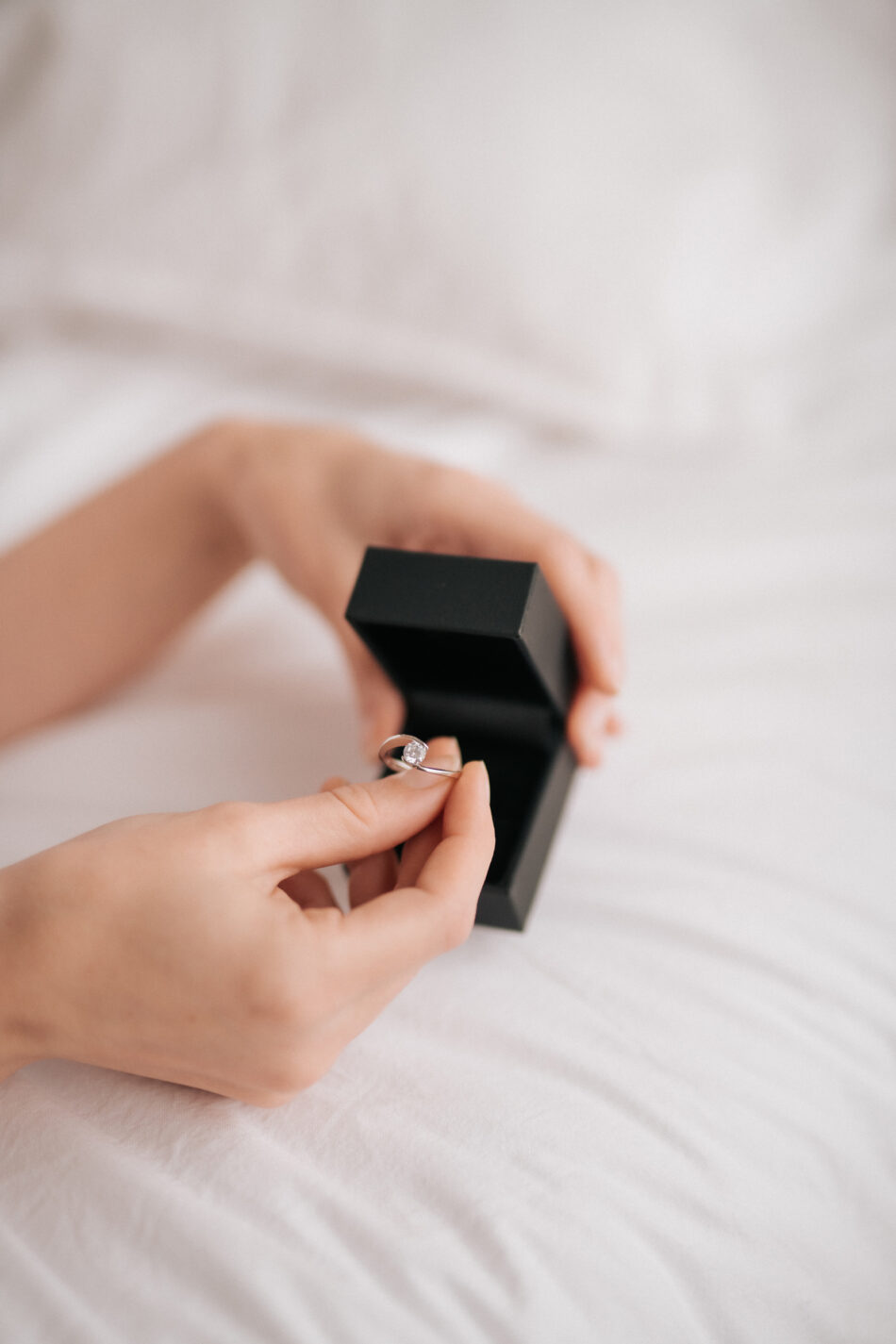 Hand nimmt Verlobungsring aus Schachtel